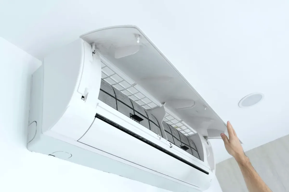 Hand opening the cover of a wall-mounted ductless air conditioner